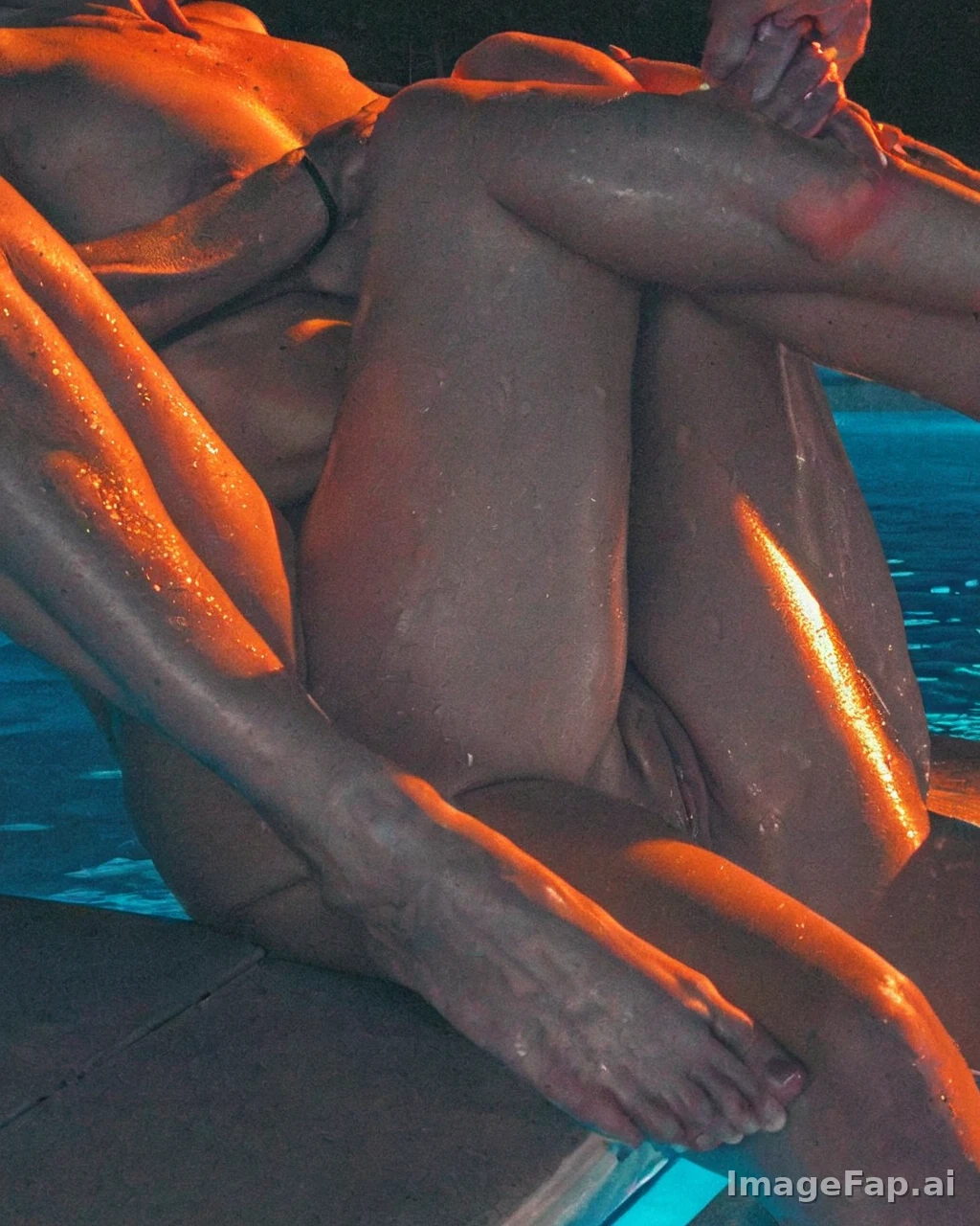 Person sitting by pool with wet skin under orange light