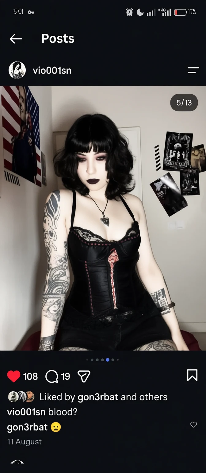 Person with tattoos wearing a black lace corset in a room with posters