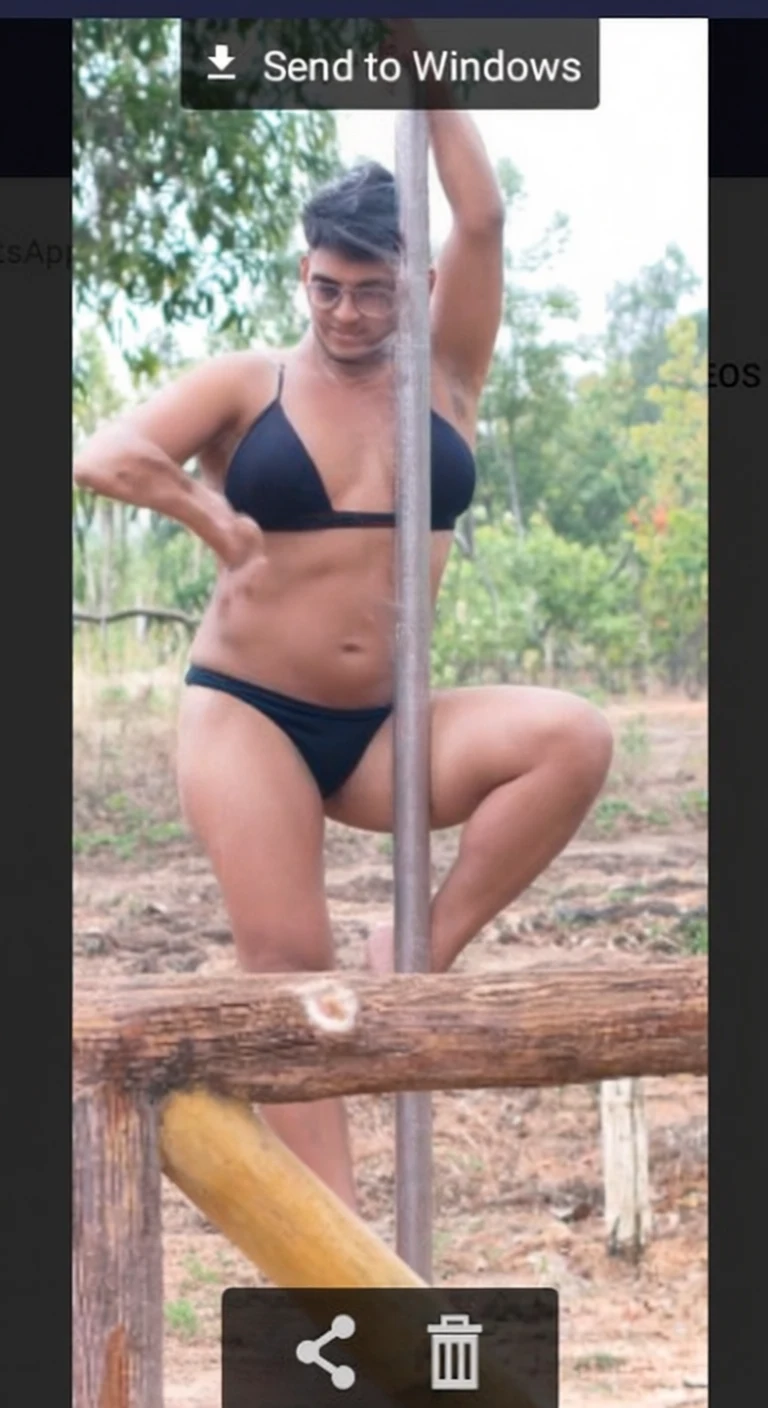 A man in a black bikini posing on a wooden structure in a sunny outdoor