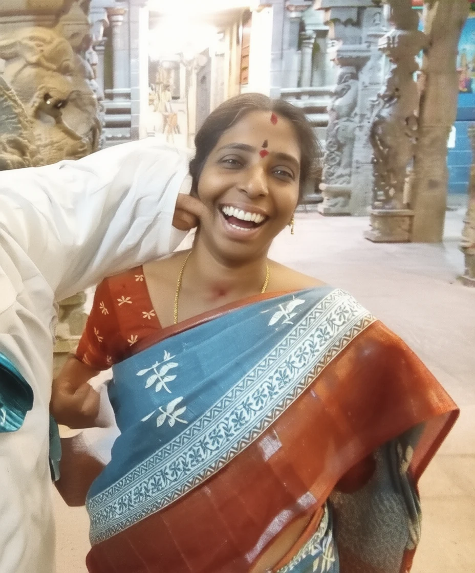 A smiling woman in traditional Indian attire inside a temple with carved